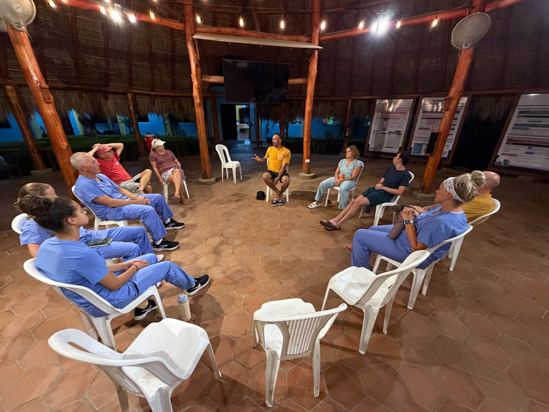Evening team circle under a thatched palapa at the Amigos for Christ compound