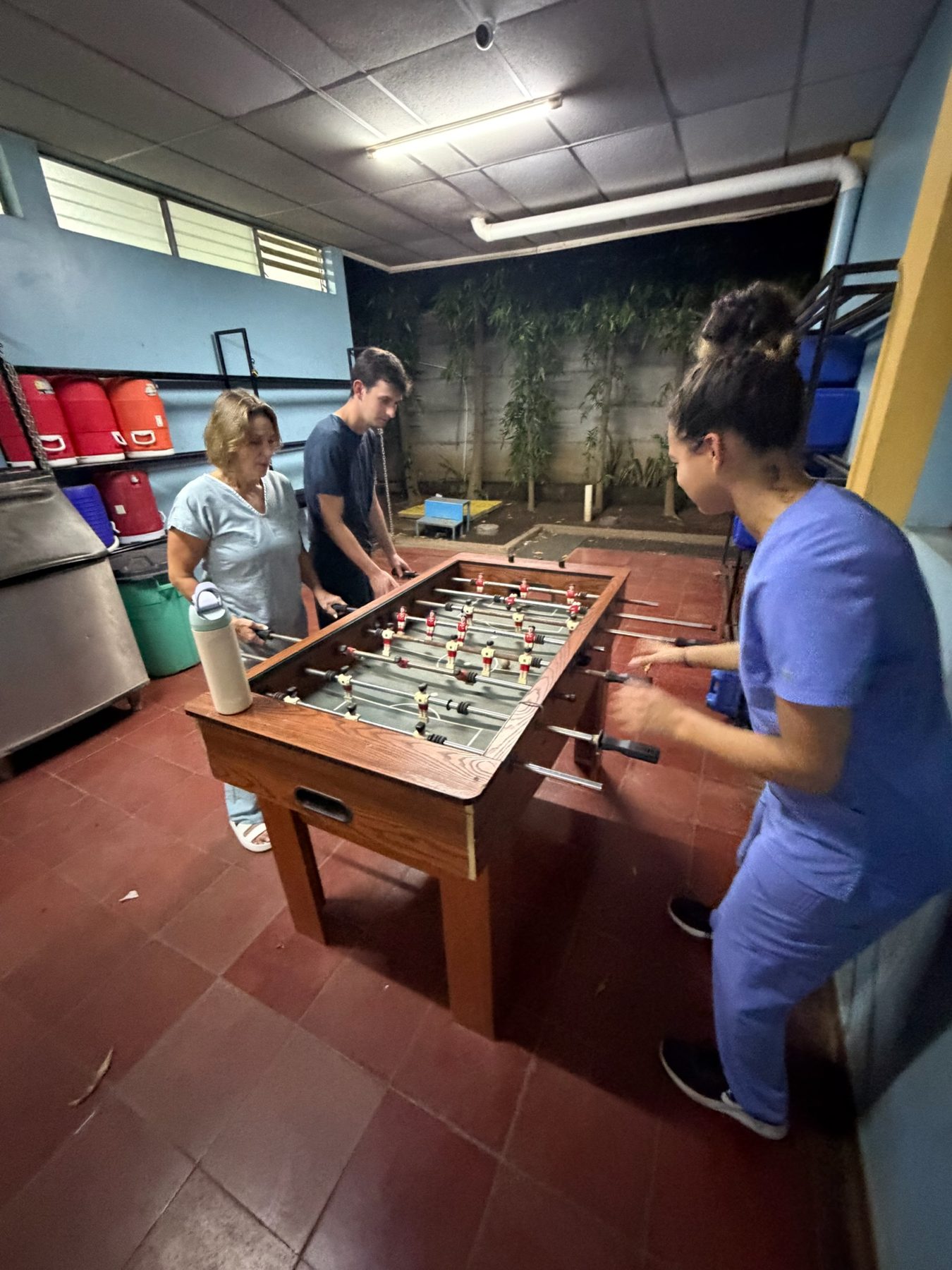 Team playing foosball at the compound, some still in scrubs