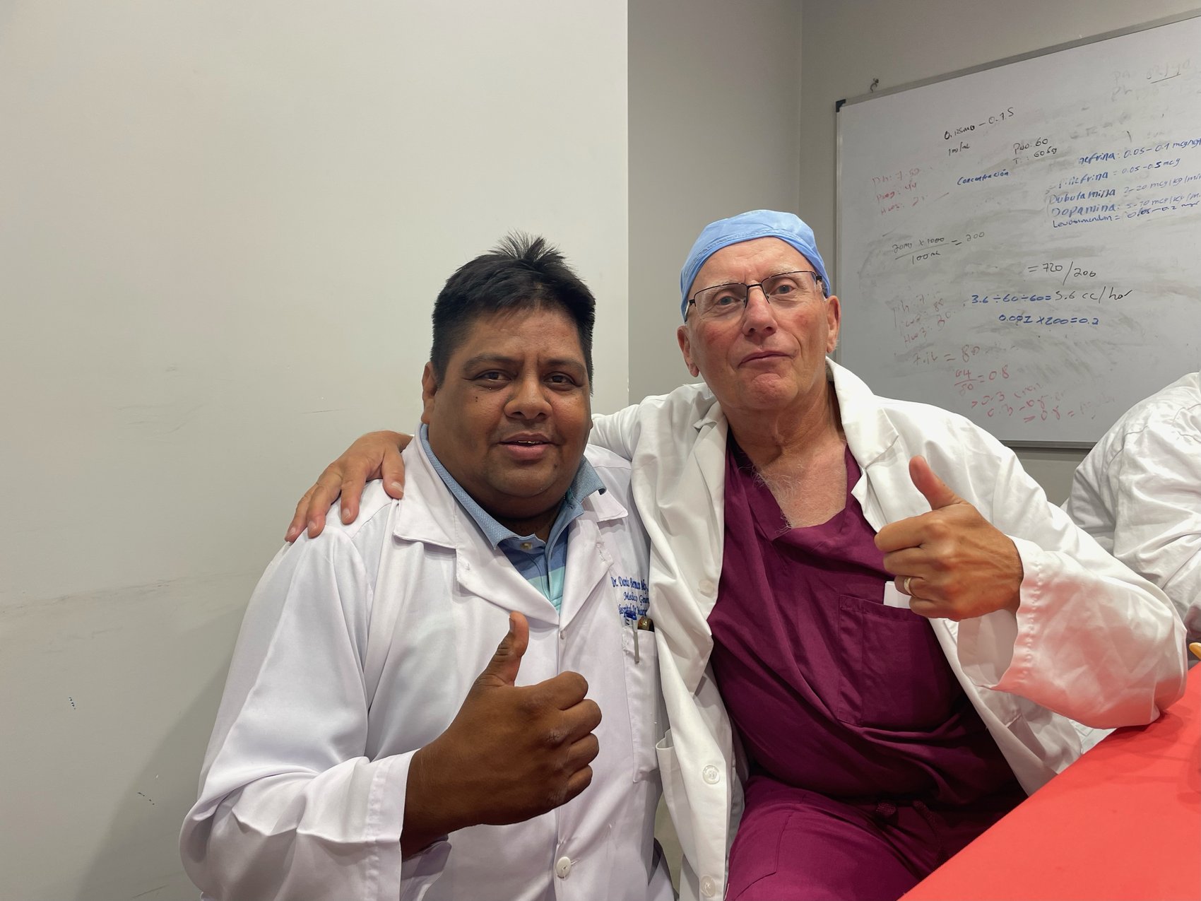 Dr. Danis Belly and Nicholas Peter Maxwell taking a break, thumbs up by a whiteboard