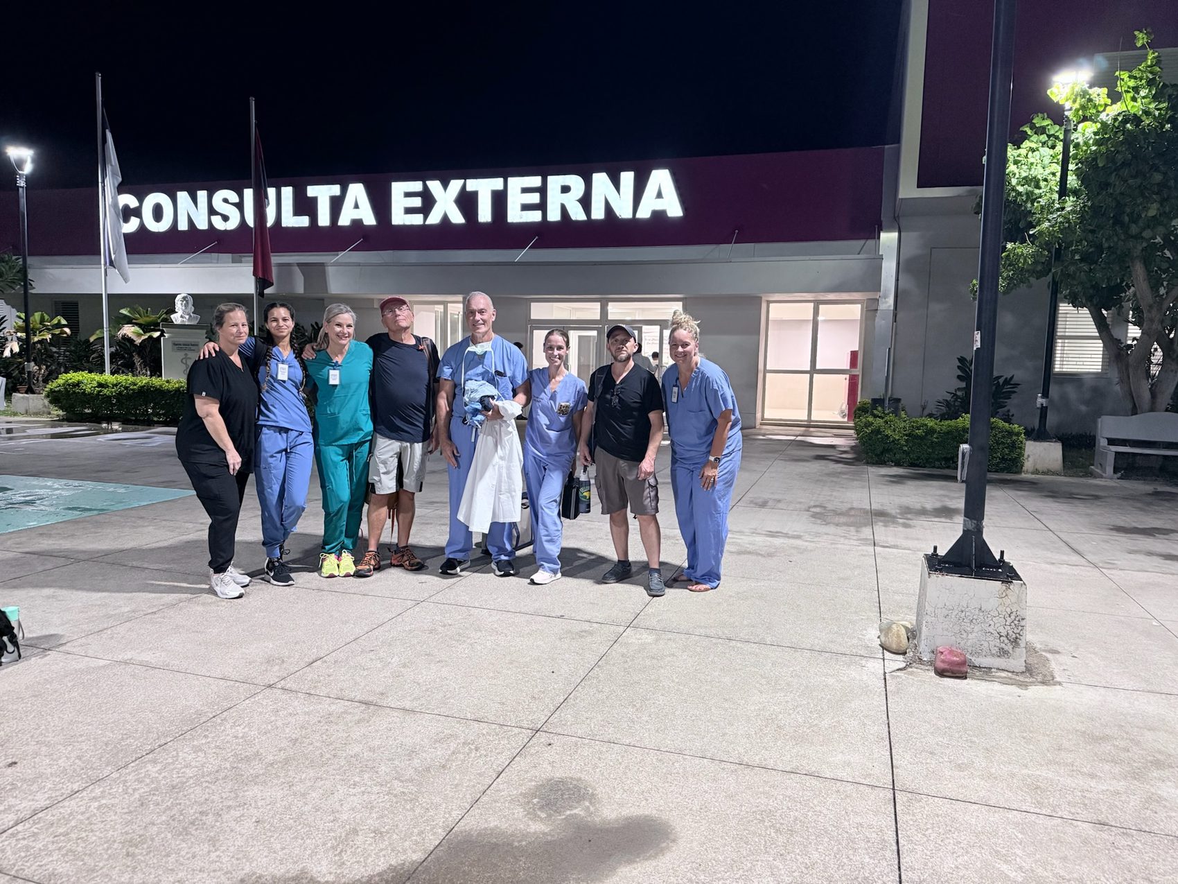 Team standing at night in front of a building marked CONSULTA EXTERNA