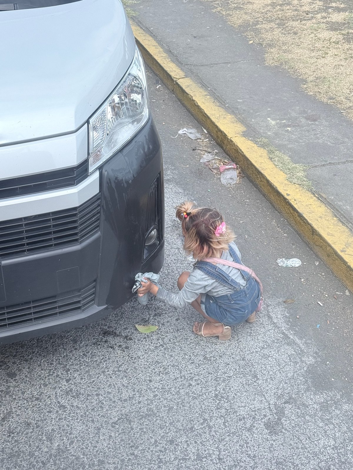 A little girl washing a car on a Managua street for money