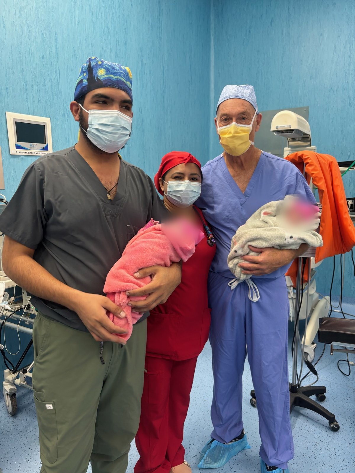 Thomas James Gallagher and colleagues holding two wrapped newborns in the hospital