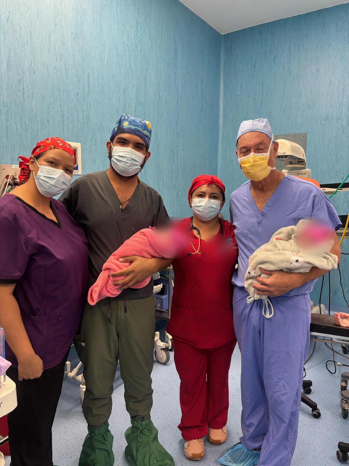 Thomas James Gallagher and three scrubbed teammates with two newborns in a hospital room