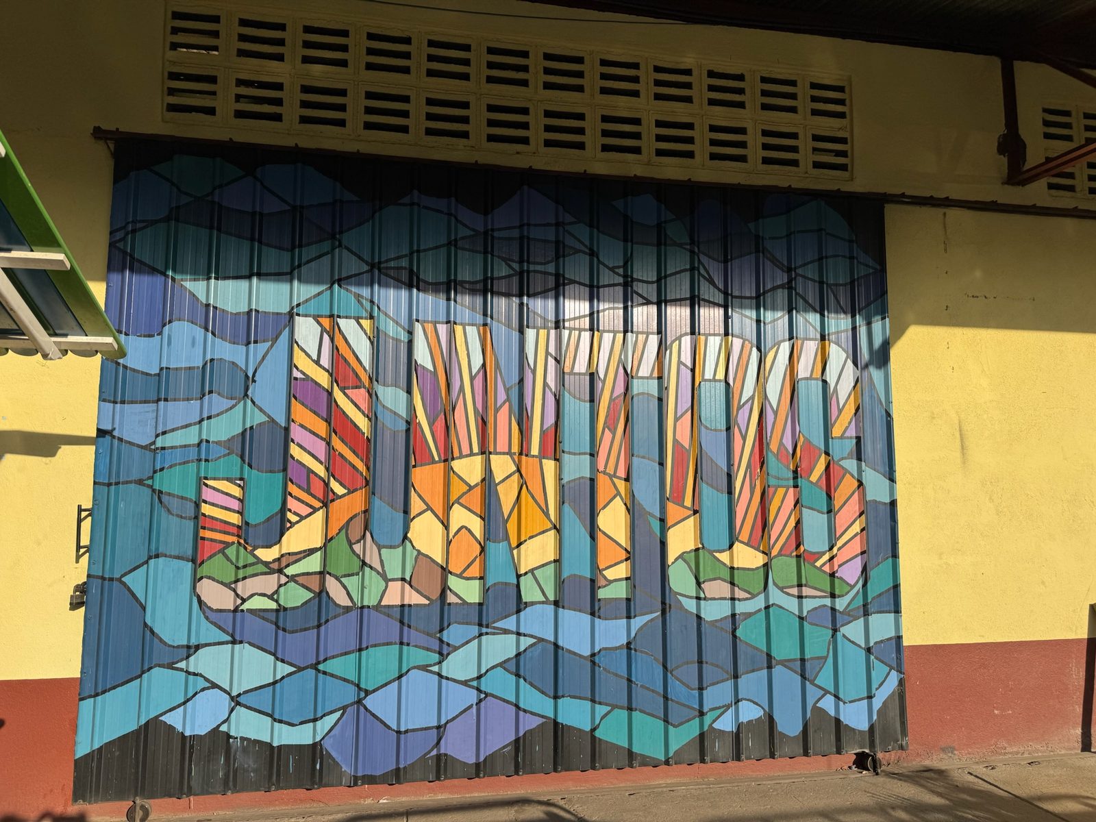 Colorful JUNTOS mural painted on a corrugated metal door