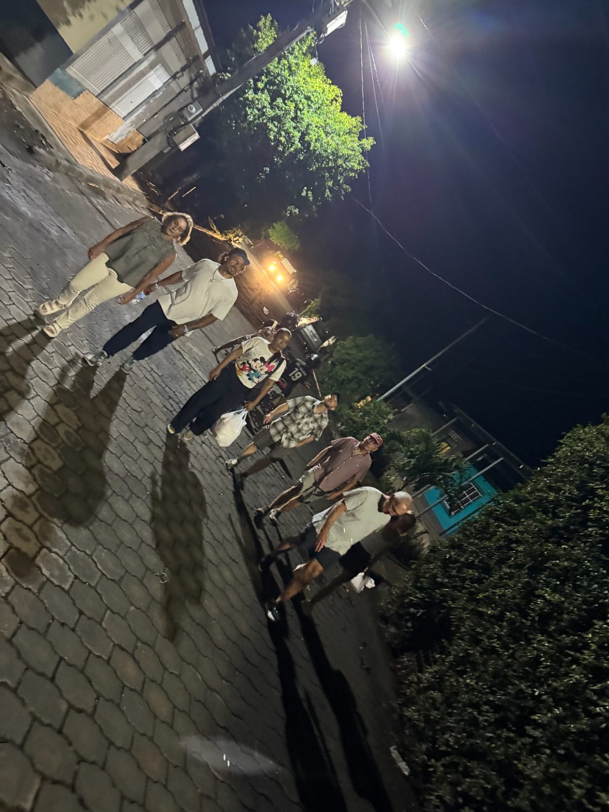 Six team members walking on a paved street at night under a bright streetlamp