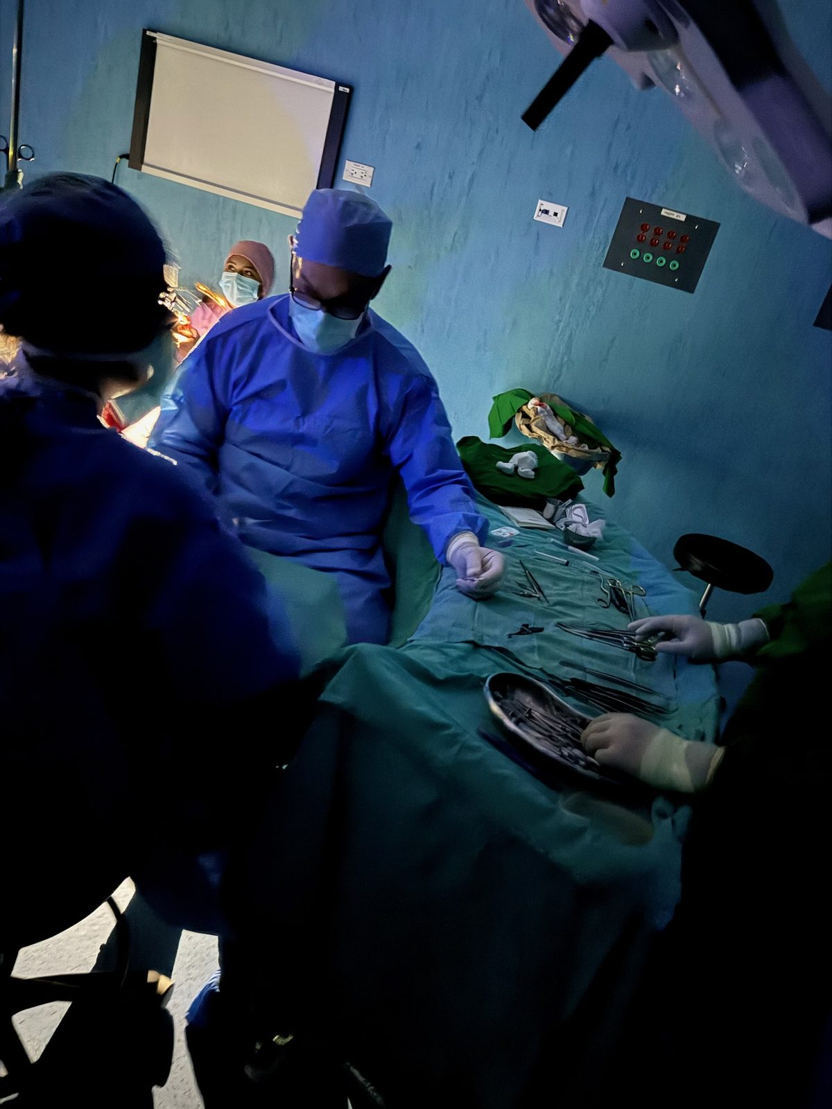 Instruments laid out on green sterile drapes with team members preparing the table