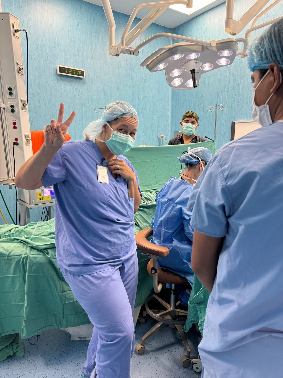 Team member making a peace sign in the operating room; no patient visible