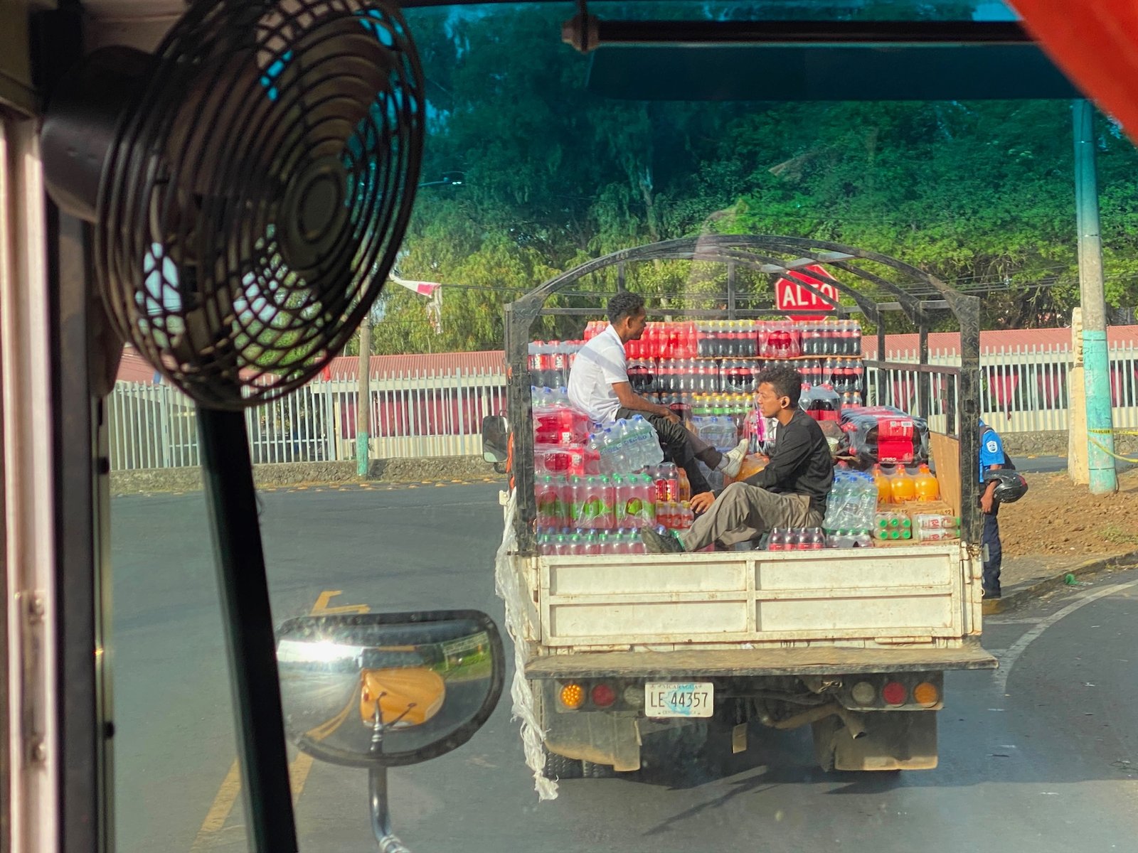 Pickup truck loaded with soda crates on a paved road seen through a windshield