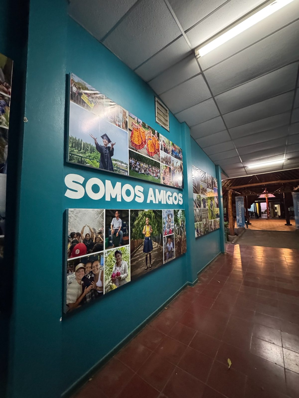 Teal hallway wall with SOMOS AMIGOS lettering and photo collages at the Amigos compound