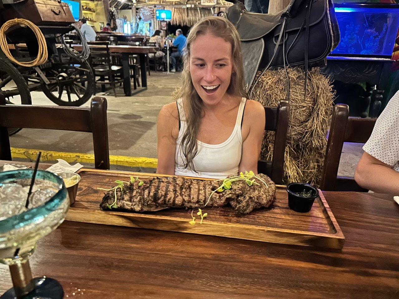 A team member surprised by a very long grilled steak on a wooden board