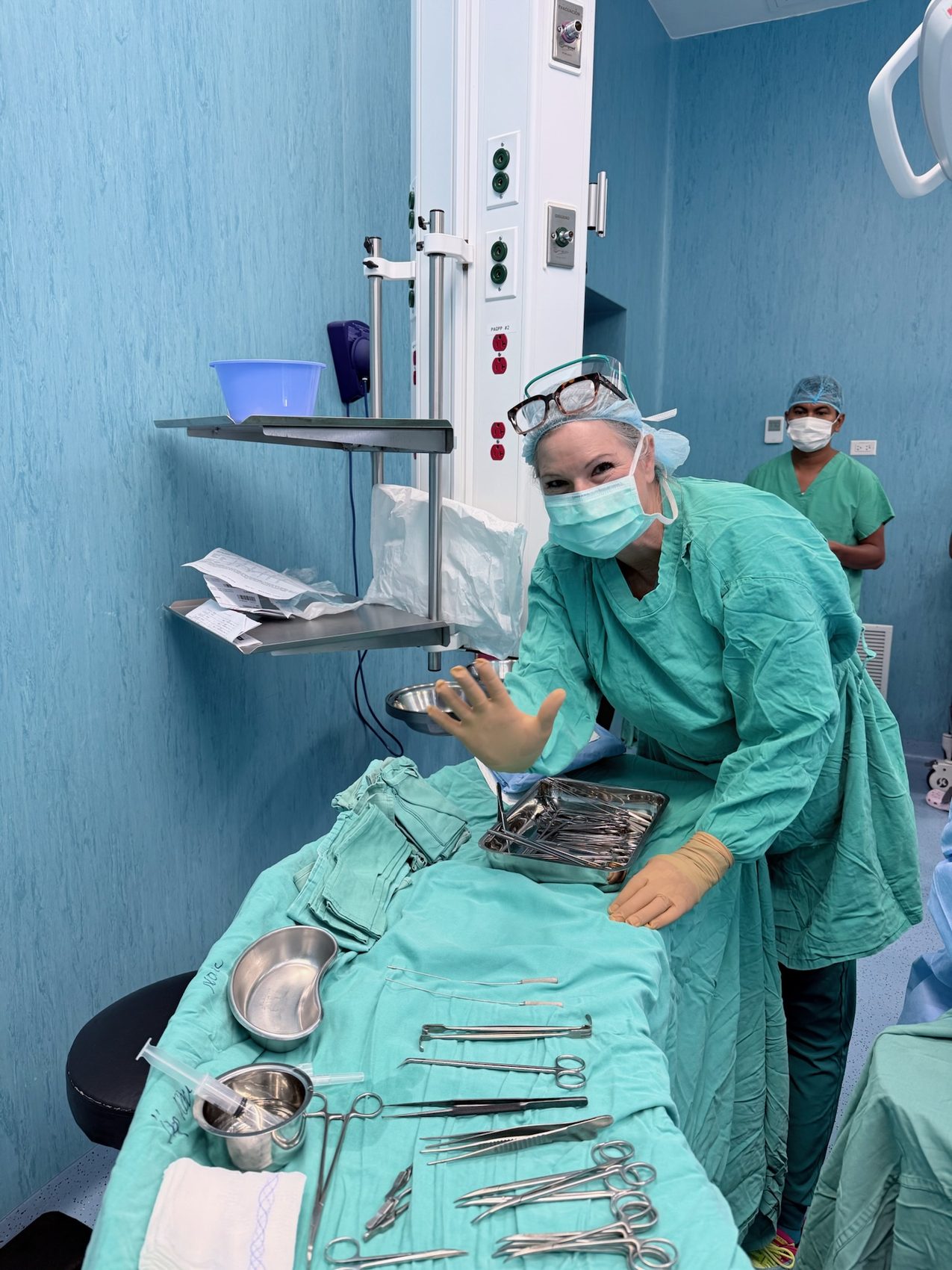 A team member in a mask laying out instruments on a teal sterile drape
