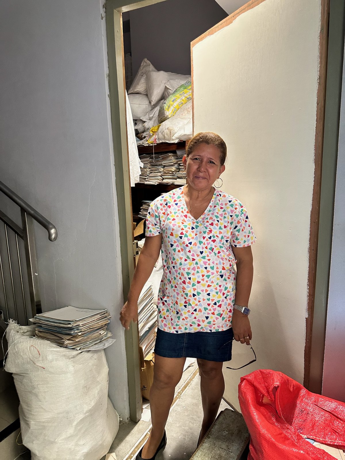 A team member in patterned scrubs standing in a doorway with supply bags behind