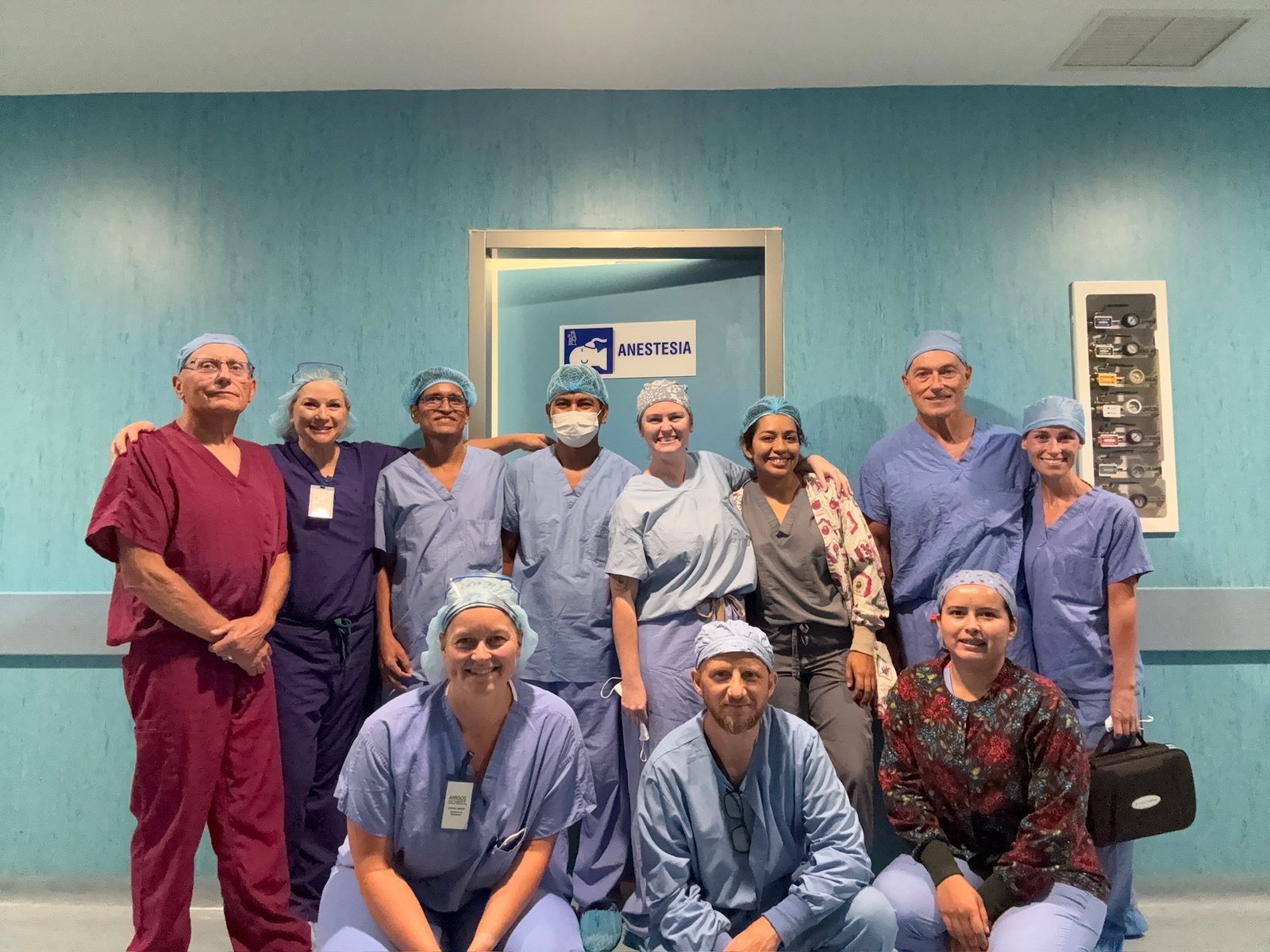 Eleven team members in scrubs posing in a hospital hallway under an ANESTESIA sign