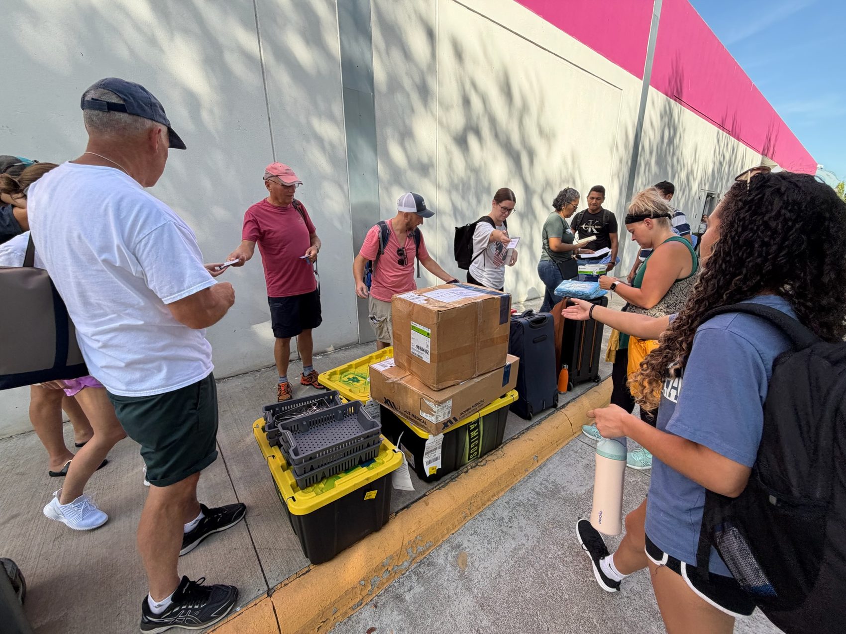 Team standing over yellow-lid bins and cardboard boxes on a sidewalk