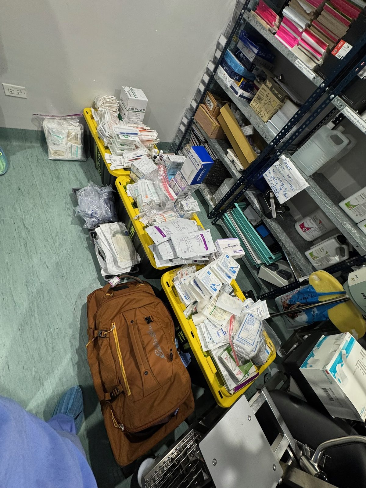 Yellow plastic bins overflowing with sterile packs next to metal supply shelves