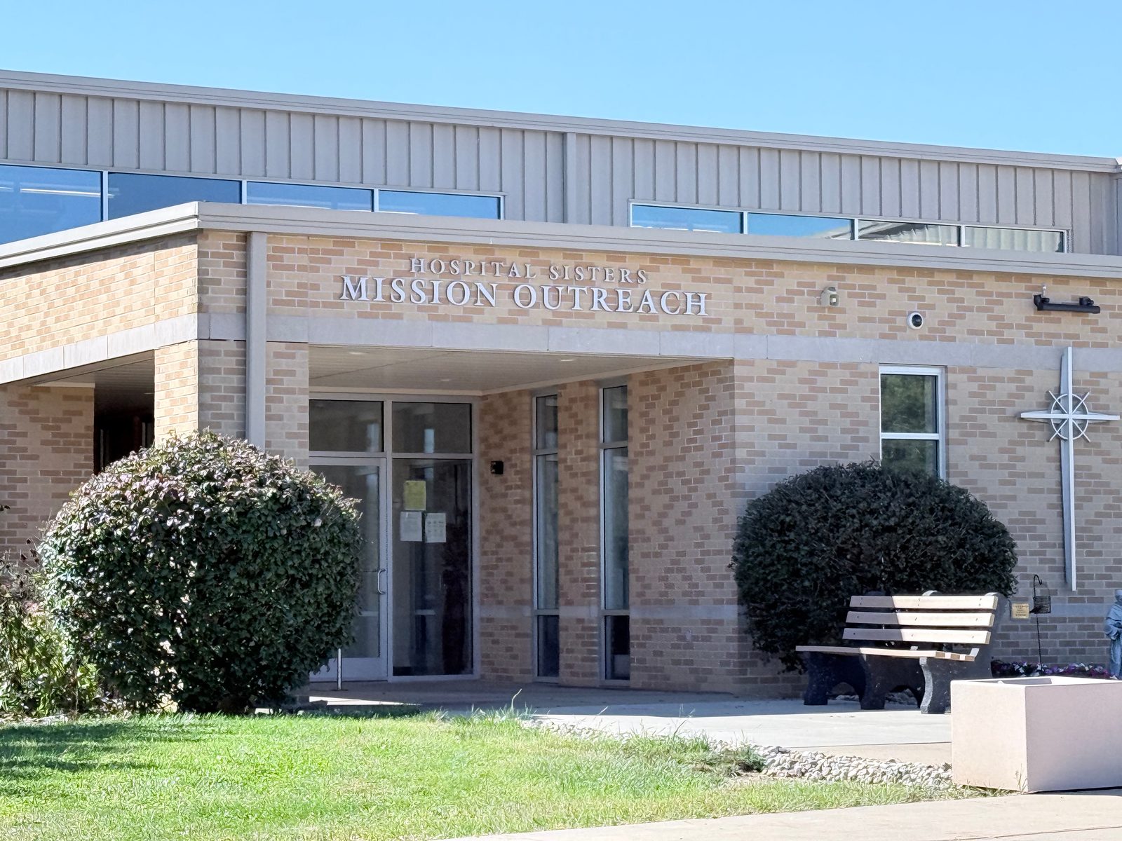 Brick entrance of the Hospital Sisters Mission Outreach building, with the organization’s name above the glass doors